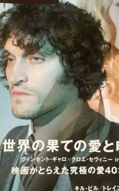 a man with curly hair wearing a suit and tie in front of a movie poster