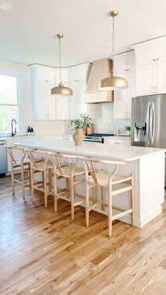 a large kitchen with white cabinets and wooden flooring, along with an island in the middle