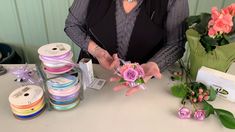 a woman is making flowers out of ribbons and other crafting supplies on a table