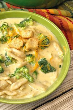 a green bowl filled with broccoli and dumplings on top of a wooden table