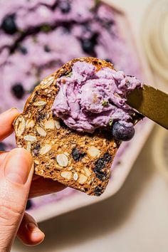 a person holding a piece of bread with blueberries on it