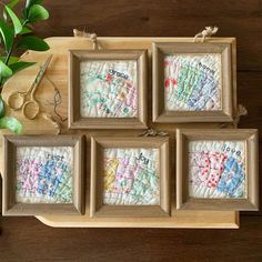 four framed cross stitch pictures sitting on top of a wooden table