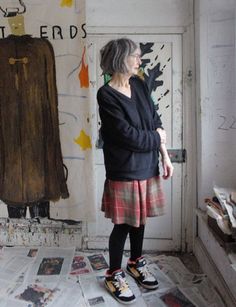 an older woman standing in front of a painting on the wall next to a door