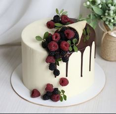 a white cake with berries and chocolate drizzle