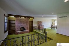 an empty living room with green carpeting and a fire place in the middle of it