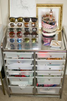 a mirrored cabinet with many pairs of sunglasses on top and other items in the bottom drawer