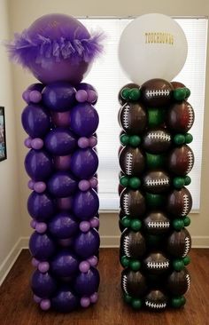 two tall purple and green balloons are in the shape of footballs, one with a white ball on top