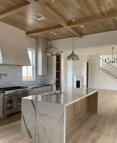 a large kitchen with an island and marble counter tops in front of the stove top oven