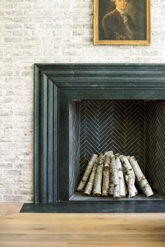 a fireplace with logs in front of it and a painting on the wall behind it