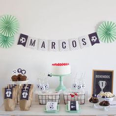 a table topped with cakes and cupcakes next to paper fan decorating on the wall