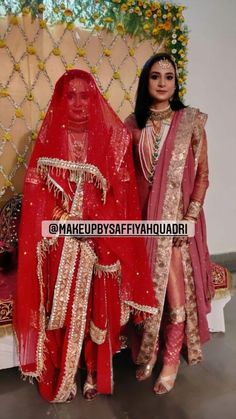 two women dressed in red and gold standing next to each other