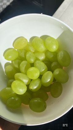 a white bowl filled with green grapes on top of a table