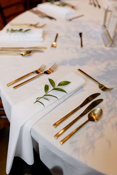 the table is set with silverware and gold utensils