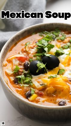 a bowl of mexican soup with black olives, cheese and cilantro on top