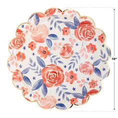 a white plate with red, blue and pink flowers on the rim is next to a ruler