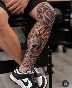 a man sitting on top of a chair with tattoos on his arm and leg behind him