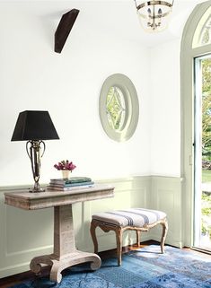 a room with a blue rug, table and chair in it next to a large window