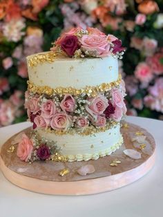 a three tiered cake with pink and gold flowers on top