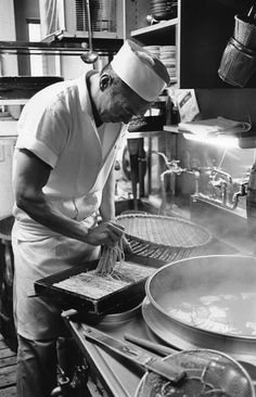 a man cooking in a large kitchen with lots of pans