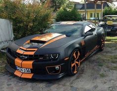 an orange and black car parked in front of a house