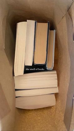 several books are sitting in a brown paper bag on top of each other, one is open and the other is closed