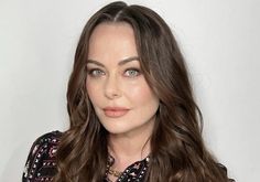 a woman with long brown hair wearing a black and white shirt looking at the camera