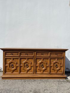 an old wooden dresser sitting in front of a white wall with carvings on the doors