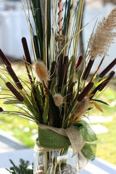 a vase filled with grass and flowers on top of a table