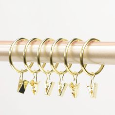 six pairs of gold earrings hanging from a curtain rod with four different charms attached to them