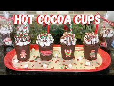 hot cocoa cups with marshmallows and candy canes on a red tray