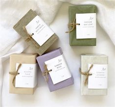 four small boxes tied with twine on top of a white cloth covered tablecloth