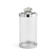 a metal canister with a flower on the top and silver foil around it's rim