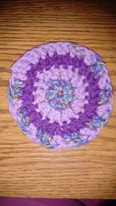 a purple crocheted dishcloth sitting on top of a wooden table