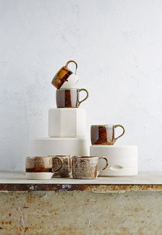 a stack of coffee mugs sitting on top of each other in front of a white wall