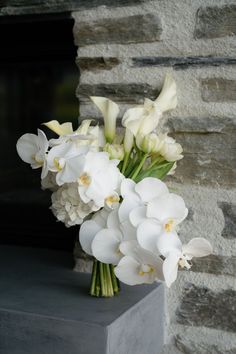 a bouquet of white flowers in front of a brick wall