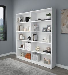 a white bookshelf filled with lots of books in a living room next to a window