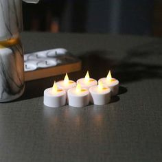 five lit candles sitting on a table next to a remote control