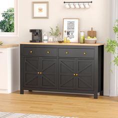 a black cabinet with yellow knobs in a white room next to a potted plant