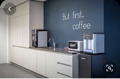 a kitchen with white cabinets and blue walls that says but first, coffee on the wall