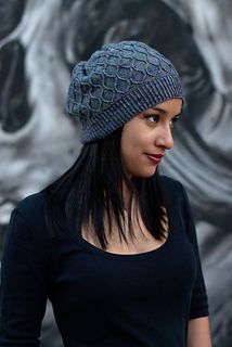 a woman wearing a knitted hat standing in front of a wall with skulls on it