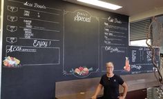 a woman standing in front of a blackboard with menus on it