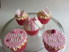 three cupcakes with pink frosting and bows are on a glass platter