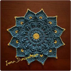 a blue crocheted doily on a wooden surface with the words tena duncan written across it