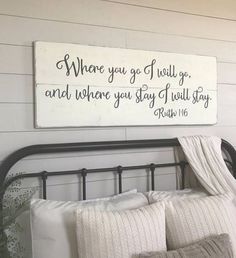 a bed with white pillows and a wooden sign above it that says where you go, if