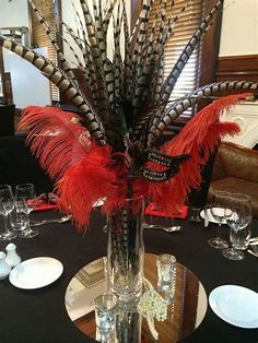 a vase filled with feathers sitting on top of a black tablecloth covered dining room