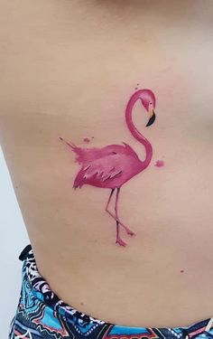 a pink flamingo tattoo on the side of a woman's stomach and chest