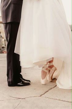 the bride and groom are holding hands while standing on their wedding day in white shoes