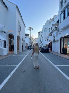 a woman walking down the middle of an empty street