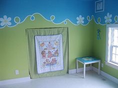 a child's room painted in green and blue with white flowers on the wall