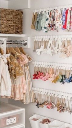 an organized closet with clothes hanging on the wall and baskets in front of it for storage